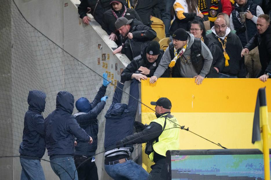 A security guard apprehends a fan who is attempting to climb over a barrier into the stands during a Germany Bundesliga 2 soccer match.