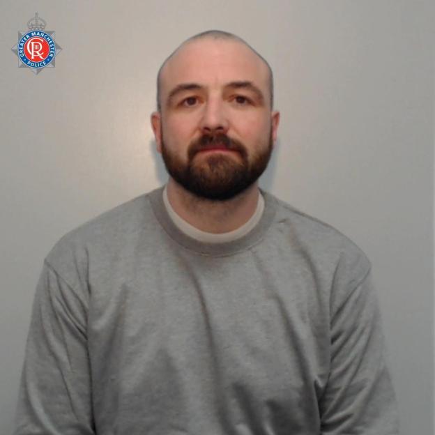 A photo of Lee Drury, a man with a beard and shaved head, wearing a gray sweatshirt, identified as a suspect in a drug empire case.