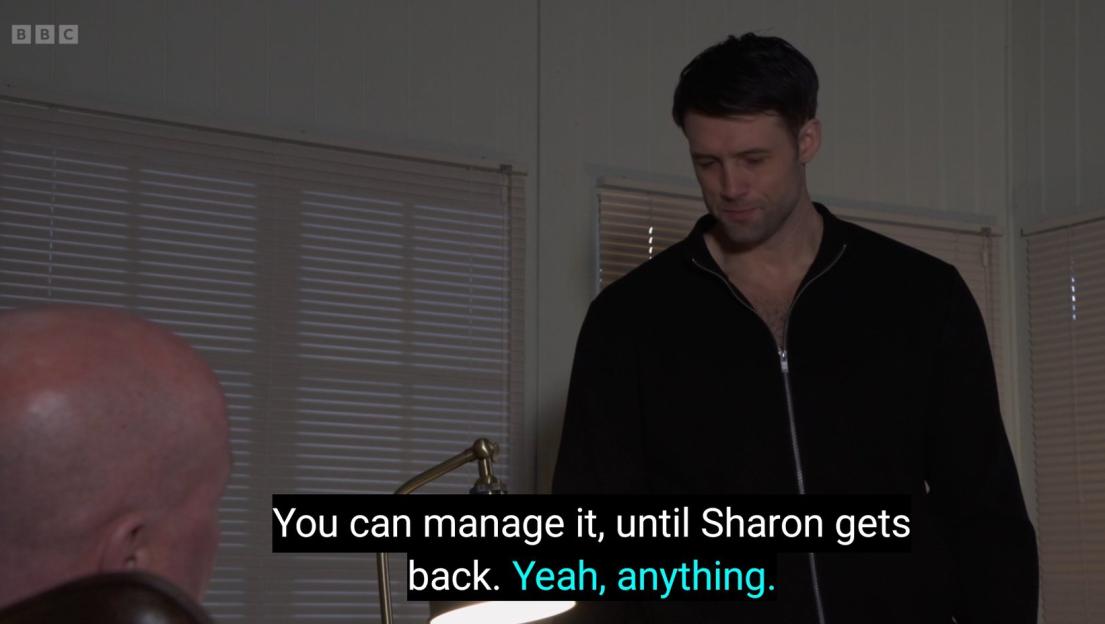 A man in a black zipped jacket talking to another person with a partial view of his head, with a caption "You can manage it, until Sharon gets back. Yeah, anything."