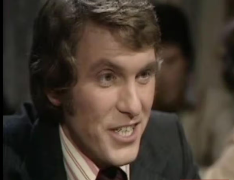 A man smiling with his mouth slightly open, showing his teeth.