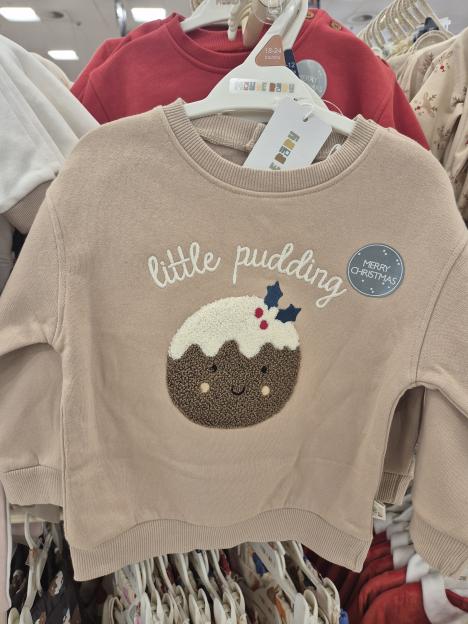 A light brown long-sleeved baby sweatshirt with "little pudding" embroidered on it, depicting a smiling Christmas pudding with white icing and holly.