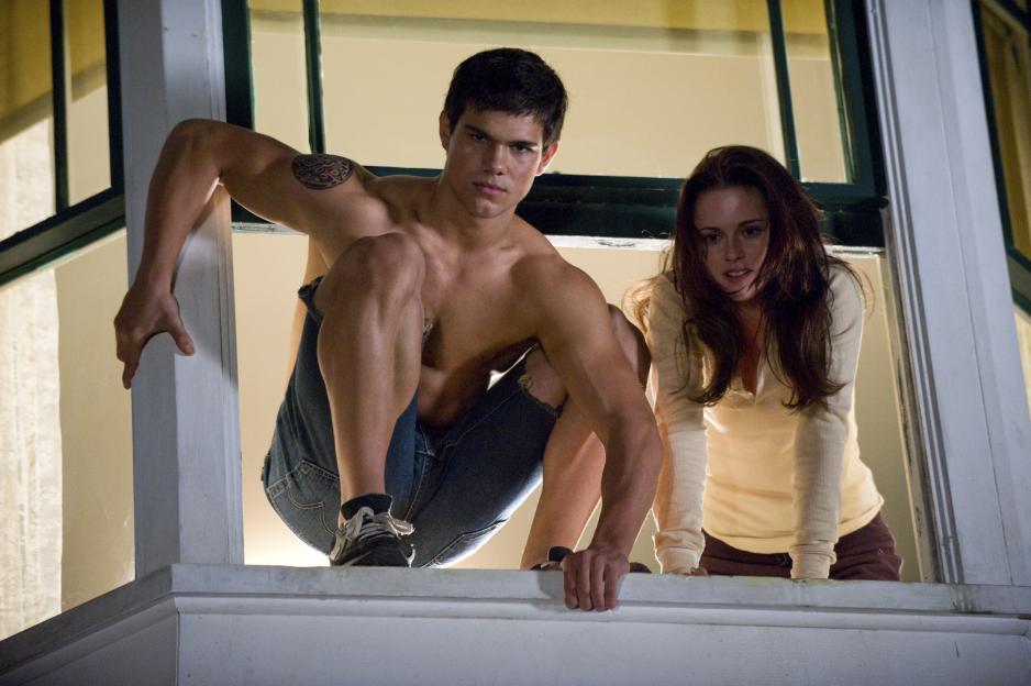 Jacob (Taylor Lautner) and Bella (Kristen Stewart) are climbing through a window in a still from the film "New Moon."