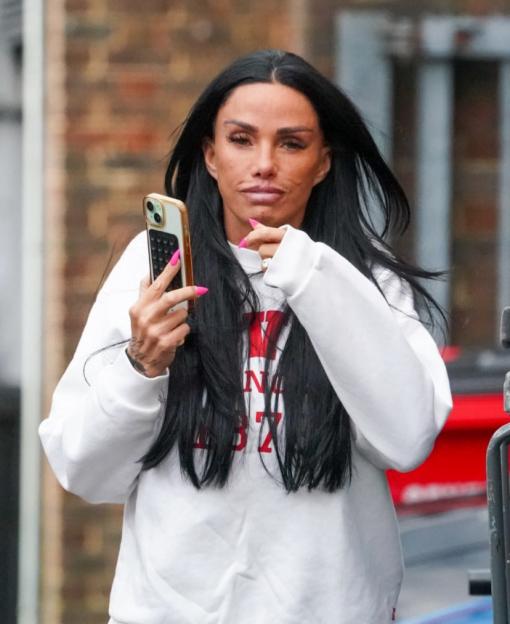 Katie Price holding a smartphone and flashing a wedding band.