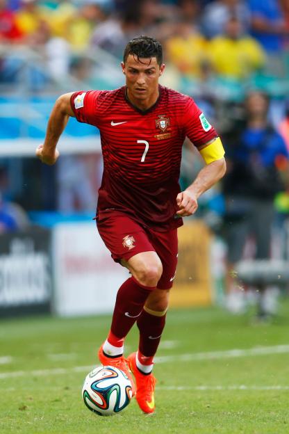 Cristiano Ronaldo in a red and dark red striped Portugal jersey, wearing a captain's armband, running with a soccer ball.