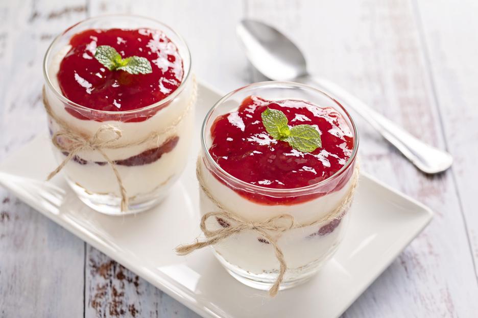 Two glasses of strawberry cheesecake on a table.