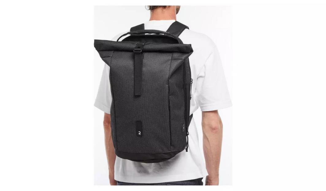 A man wearing a black backpack and a white t-shirt.