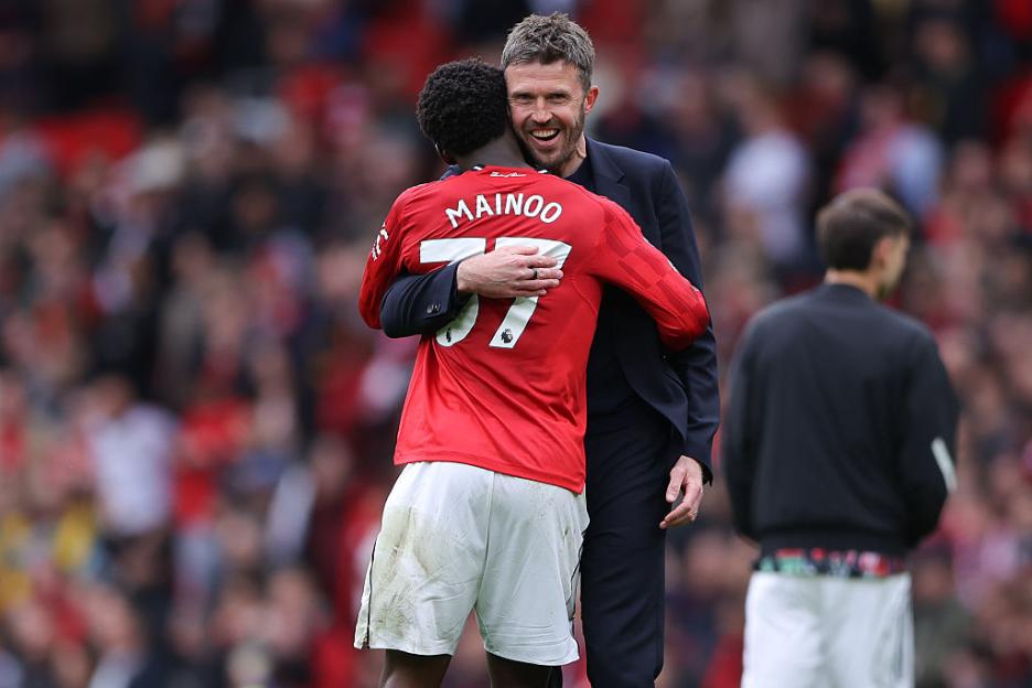 Manchester United player Kobbie Mainoo embraces coach Michael Carrick.