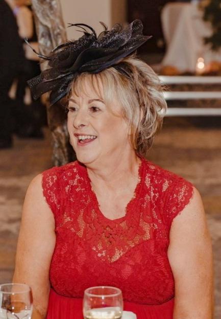 Karen Kimblin, a woman with short blonde hair and a black fascinator, smiling.