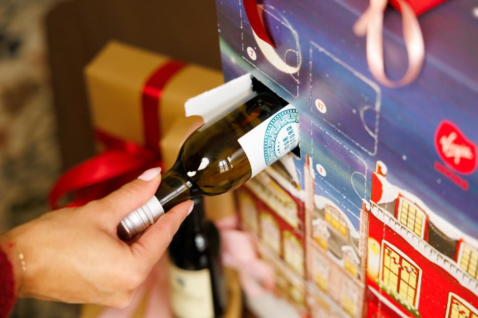 A hand pulling a bottle of wine from a Virgin Wine Advent Calendar.