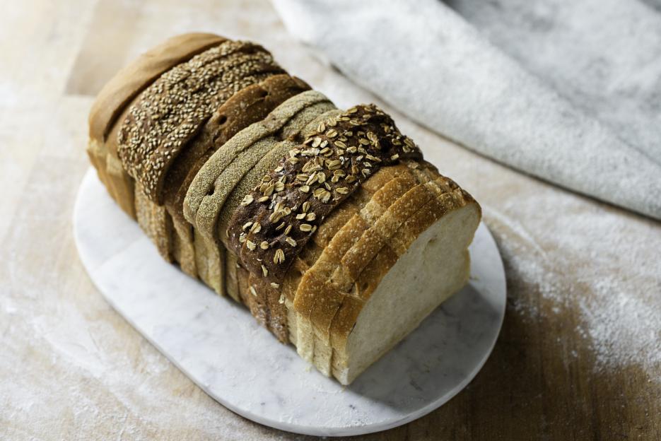 Sliced loaf made up of variety of white and wholemeal slices on cutting board, high angle view