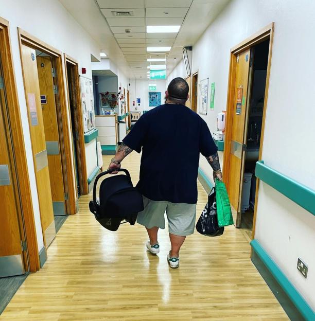 Nick Frost carrying his newborn in a car seat out of the hospital.