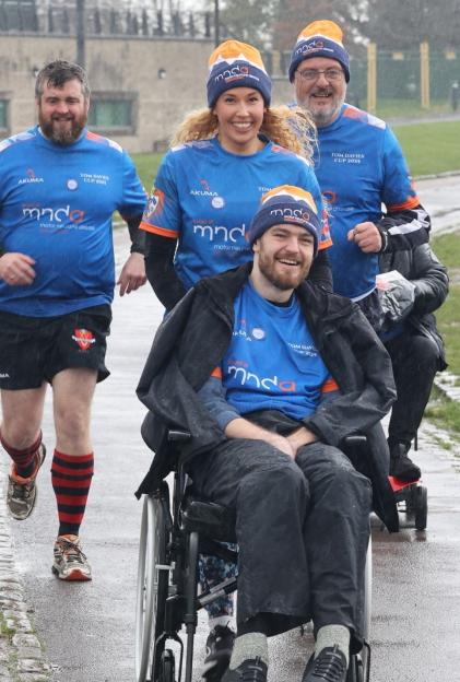 Tom Davies in a wheelchair, with his girlfriend Alex Ross and two others, participating in a charity run to raise awareness for Motor Neurone Disease.