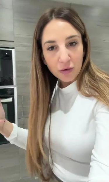 A woman in a white long-sleeved shirt looking at the camera with a serious expression.