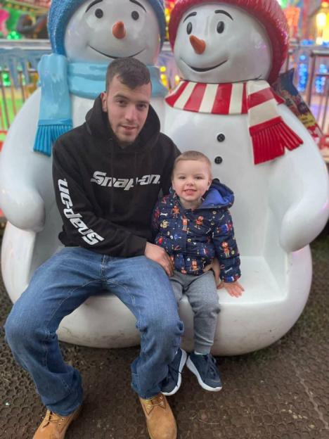 A man and a toddler sit on a snowman bench.