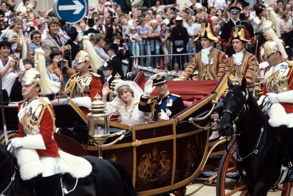 Princess Diana and Prince Charles in a horse-drawn carriage after their wedding, waving to crowds.