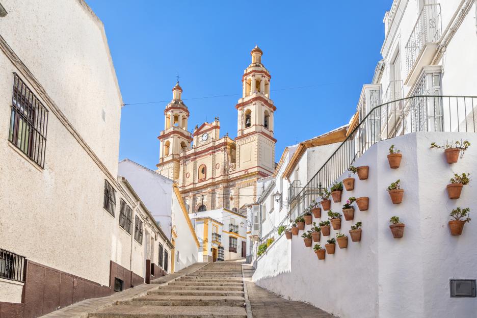 Church of Our Lady of Incarnation in Olvera, Cadiz province, Andalusia, Spain, seen from a street with stairs and white buildings.