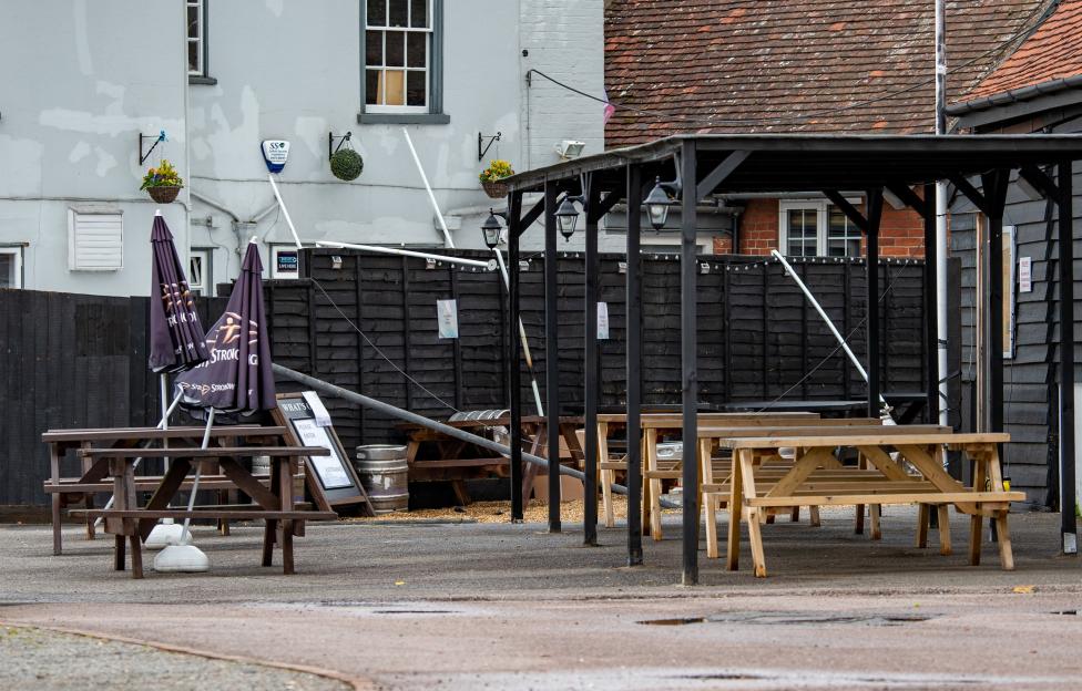 The Kings Head pub in Great Cornard, Suffolk, showing its outdoor seating area with picnic tables and closed umbrellas.