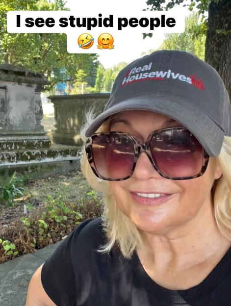 A woman wearing a "Real Housewives" baseball cap and large sunglasses smiles at the camera, with a caption "I see stupid people" above her head.