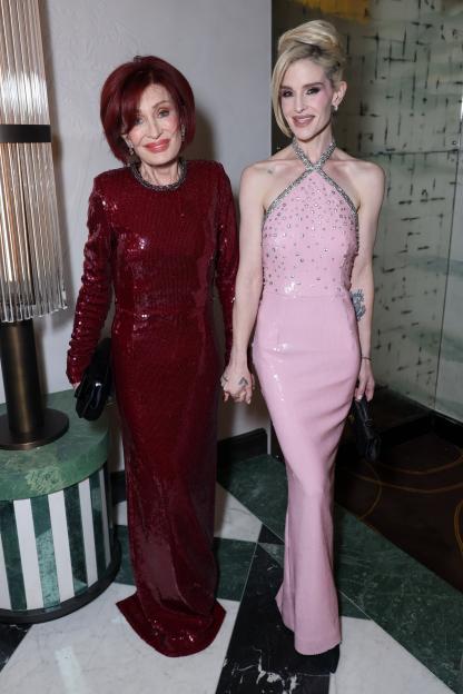 Sharon Osbourne in a red sequin gown and Kelly Osbourne in a pink sequin halter dress pose together.