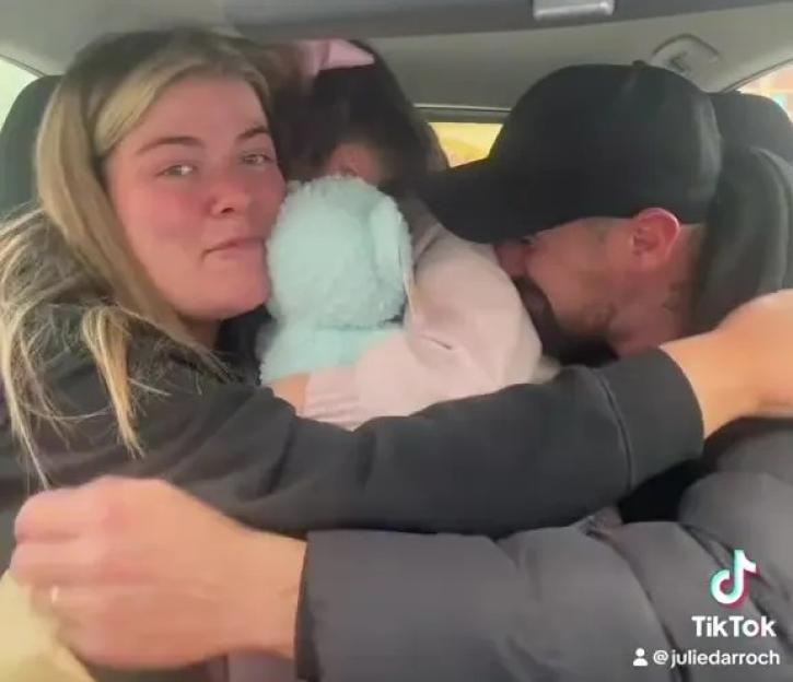 A couple and their child embracing in a car.