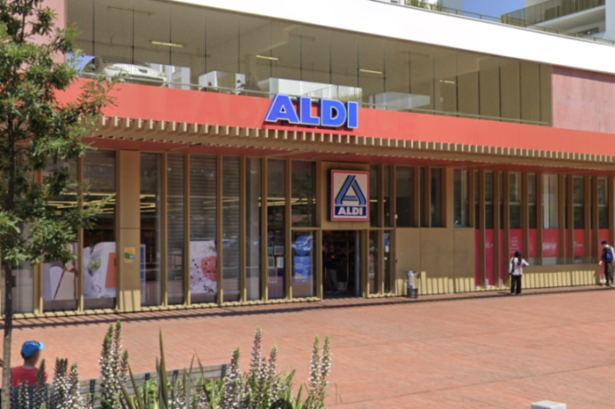 Exterior view of an Aldi supermarket with a large blue sign and a red awning.