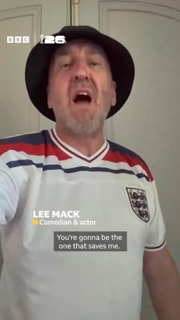Comedian Lee Mack wearing a bucket hat and a white England football shirt.