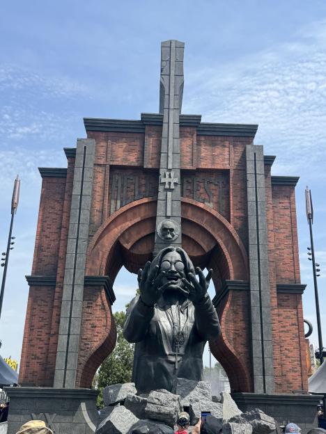 Statue of Ozzy Osbourne with a large brick structure and "HELLFEST" logo behind it.