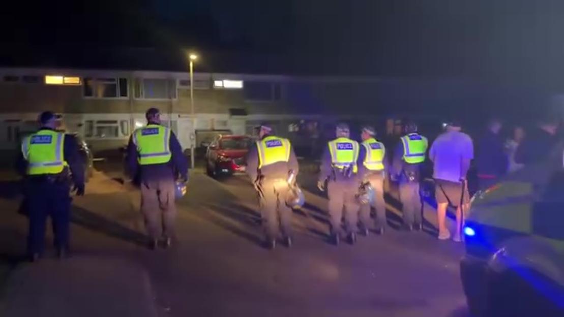 Police officers escorting individuals to safety at night.