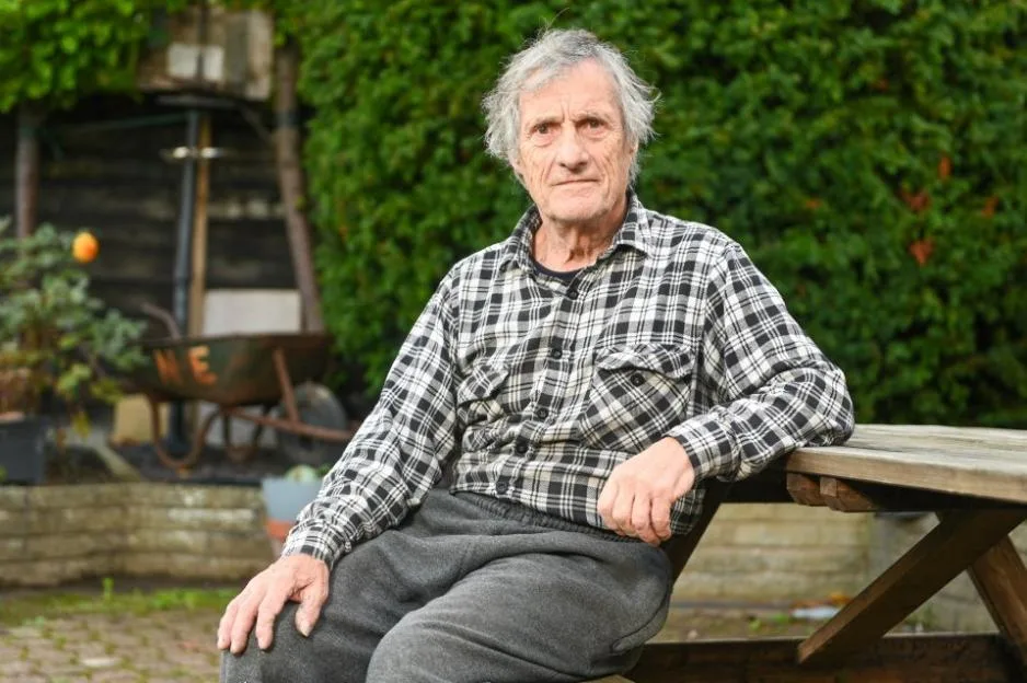 David Mayhew sitting outdoors near a chemical plant.