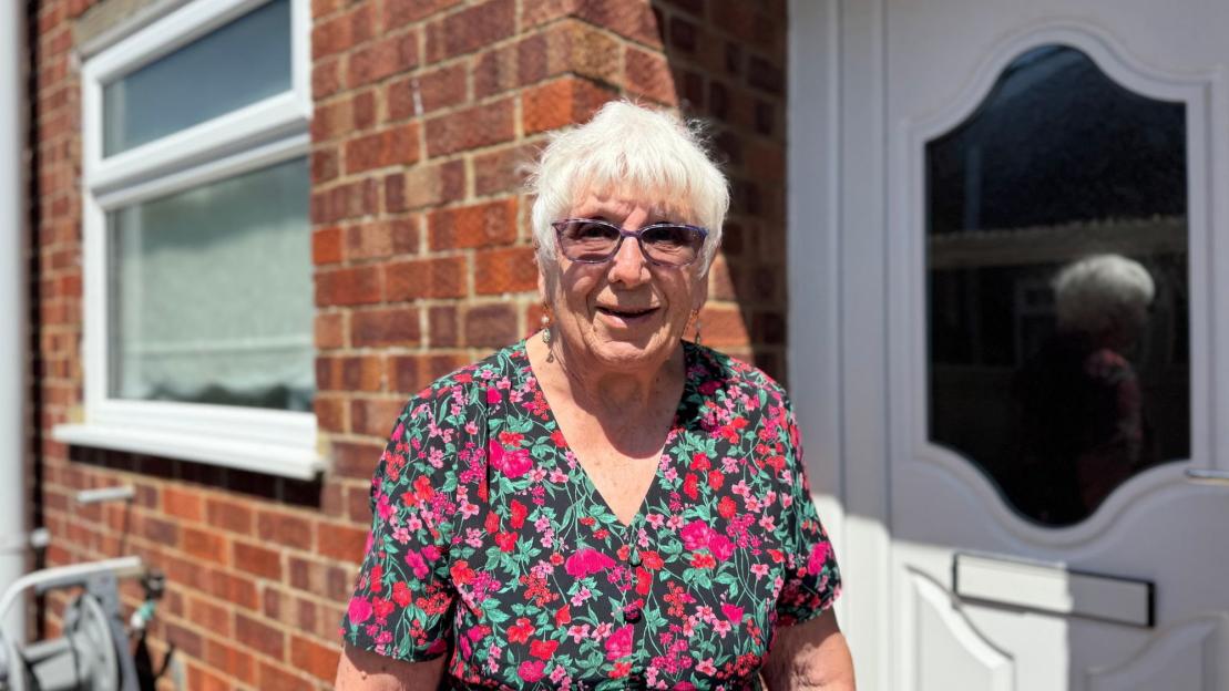 Rosemary Vincent, a villager, standing outside a brick building.