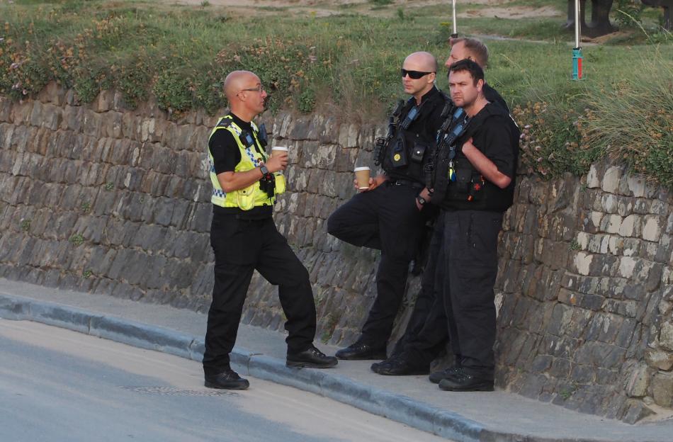 Police officers gathered near a stone wall.