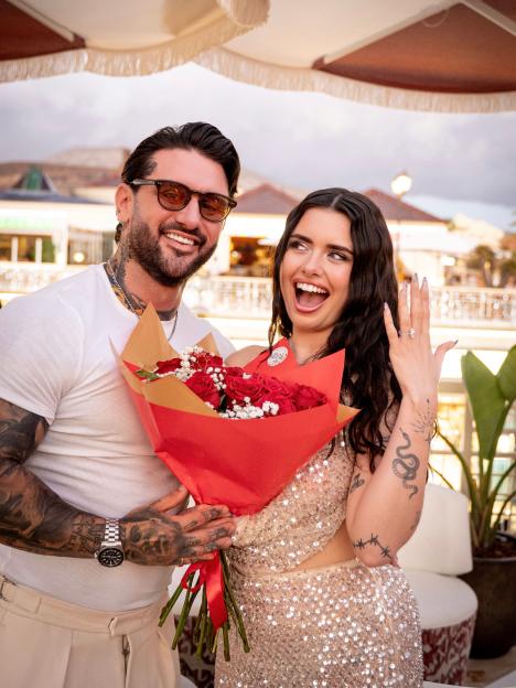 Danny Andrews and Sadie Bass pose with an engagement ring and red roses.