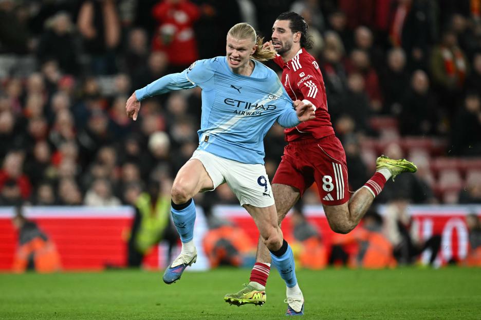 Liverpool's Dominik Szoboszlai fouls Manchester City's Erling Haaland during a football match.