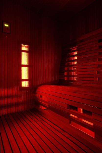 Infrared sauna cabin illuminated by red light.