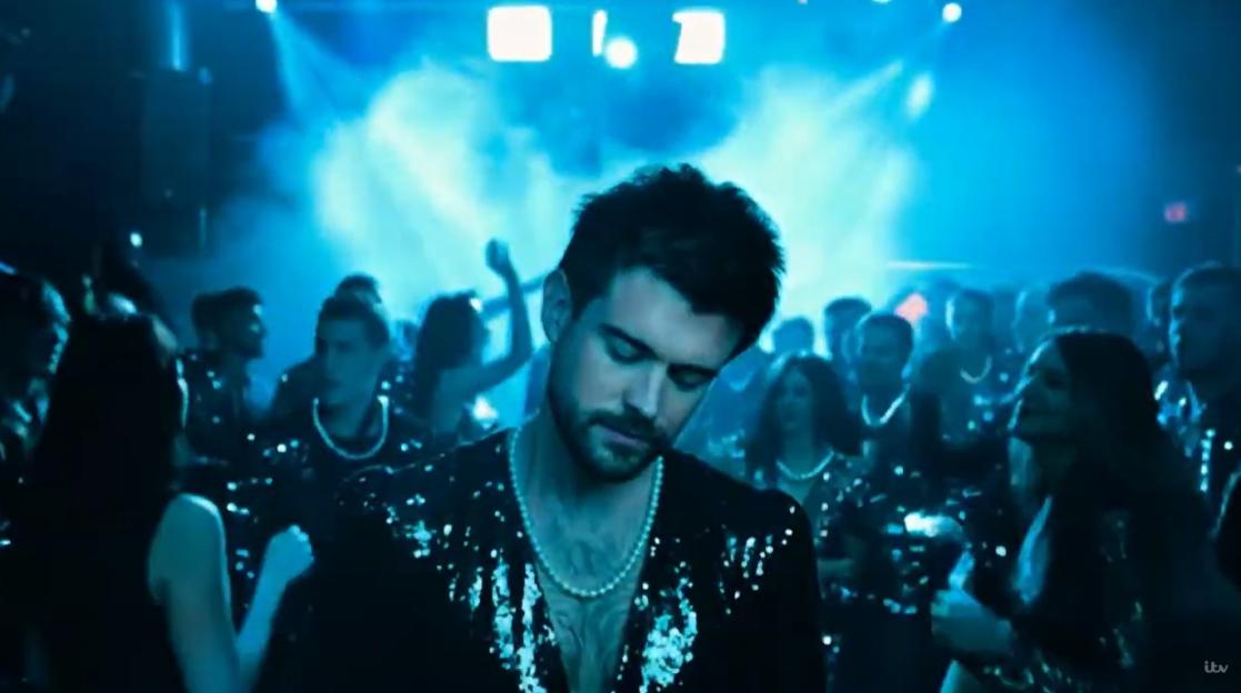 Jack Whitehall in a pearl necklace and sequined jacket in a club.