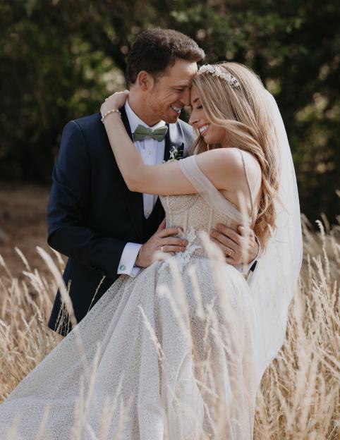 Stacey Solomon and Joe Swash embrace at their wedding in a field of tall grass.