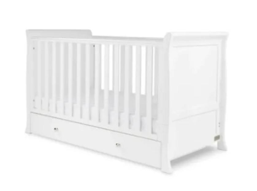 a white crib with a drawer underneath it on a white background .