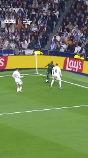 Three football players near the corner flag during a Champions League match.