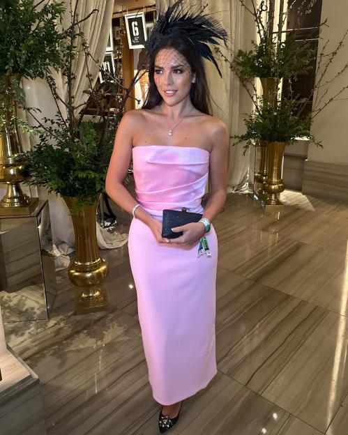 Gemma Owen in a light pink strapless dress, black fascinator, and a black clutch.