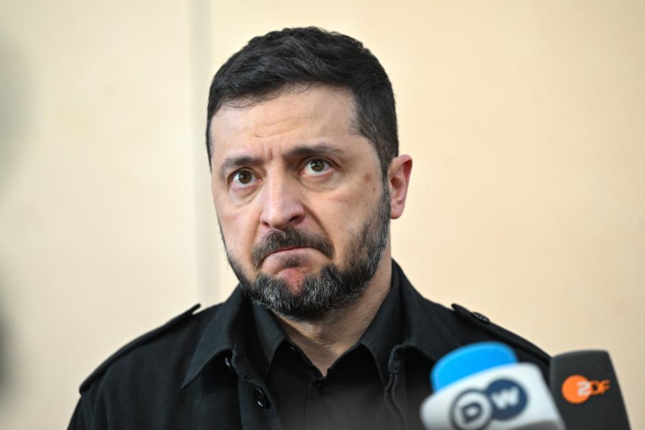 Ukrainian President Volodymyr Zelenskyy speaking to media with microphones from DW and 2DF visible.