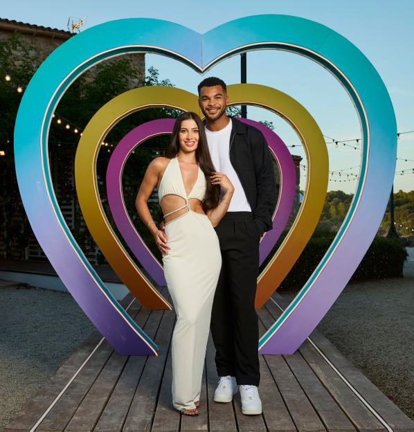 Yasmin Pettet and Jamie Rhodes pose in front of a heart-shaped arch on the 'Love Island' TV show set.