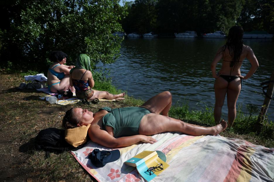 People sunbathing by the River Thames at Teddington Lock.