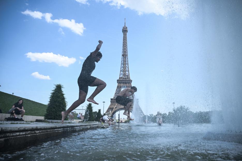 People jumping into the Trocadero Fountain near the Eiffel Tower during a heatwave.