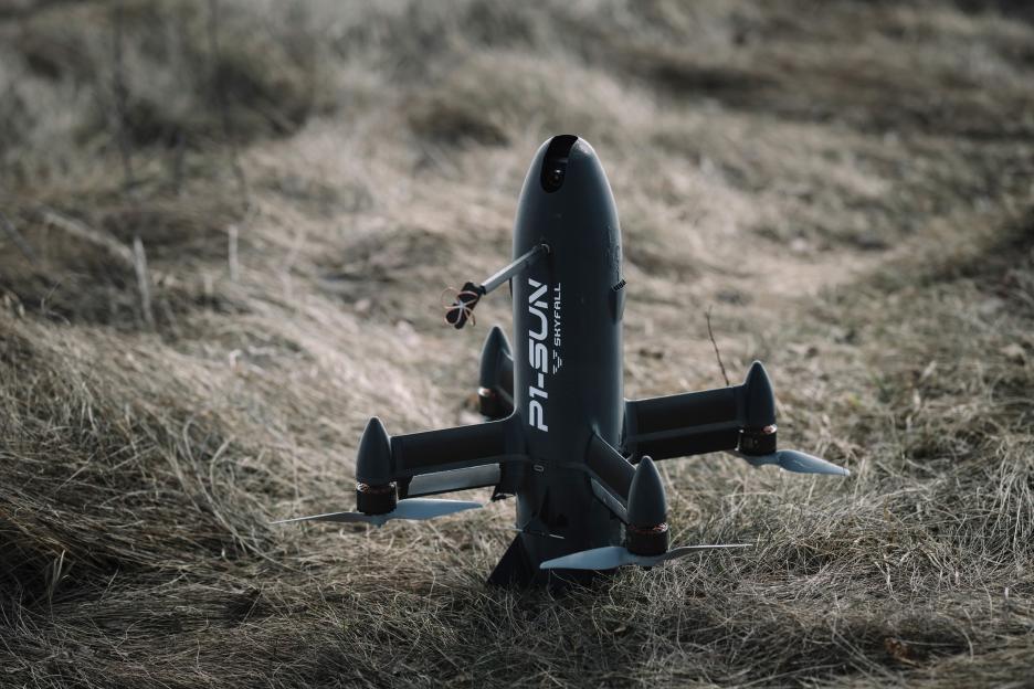 A black P1-Sun interceptor drone sitting in dry grass during trials.