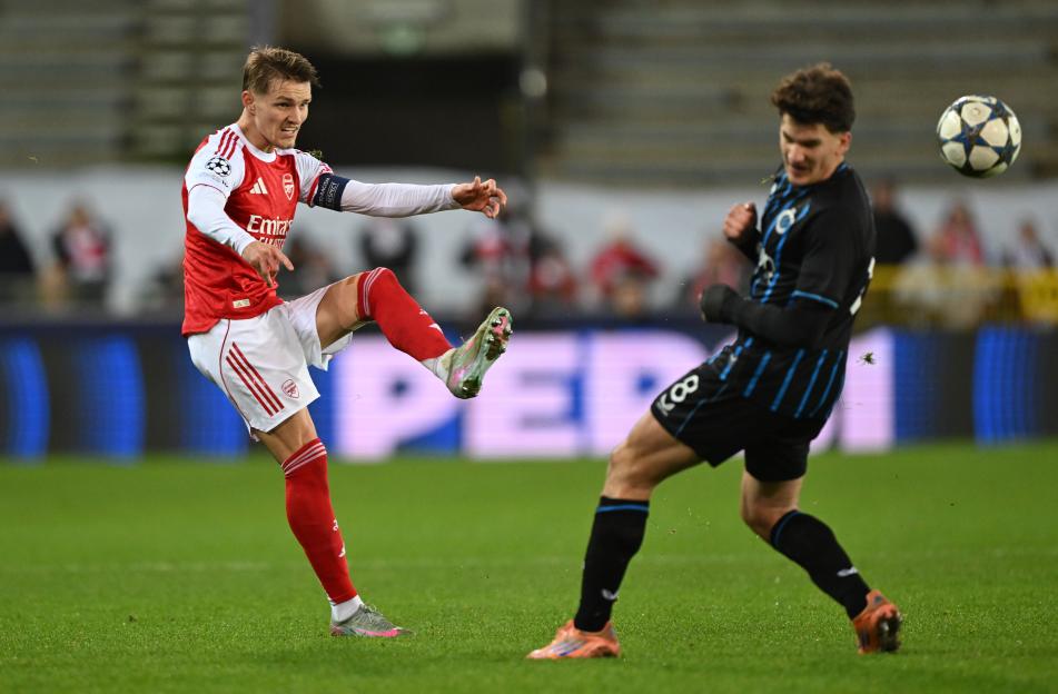 Martin Odegaard of Arsenal kicking the ball during a UEFA Champions League match.