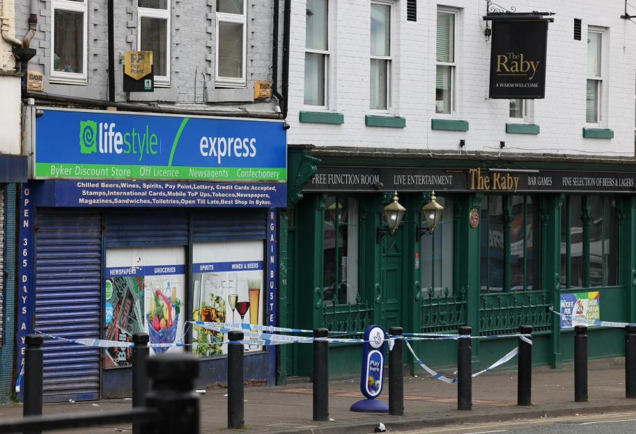 Police tape blocking access to a storefront and pub after an assault.