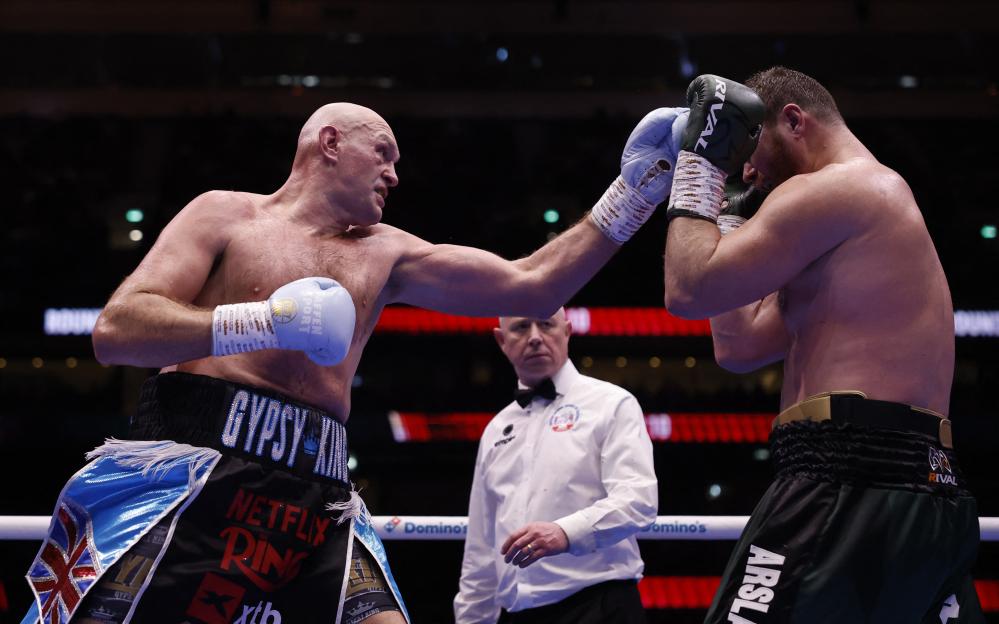 Tyson Fury throws a punch at Arslanbek Makhmudov in a boxing match.
