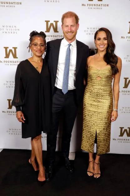 Doria Ragland, Prince Harry, and Meghan, The Duchess of Sussex posing together at an awards event.