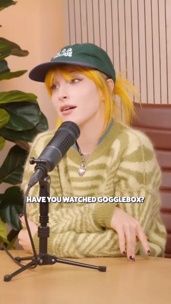 Hayley Williams from Paramore wearing a green cap and green and white sweater, speaking into a microphone.
