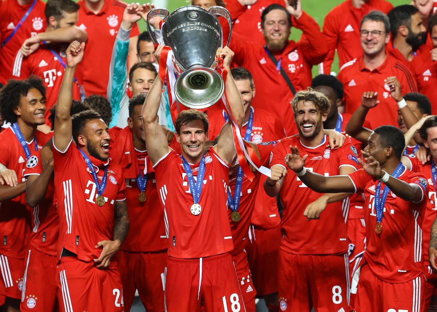 Leon Goretzka of FC Bayern Munich lifts the UEFA Champions League Trophy, surrounded by his cheering teammates.